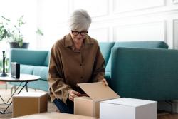 woman-unpacking-brown-boxes-living-room.jpg XHow To Prepare for a Stress-free Downsizing
